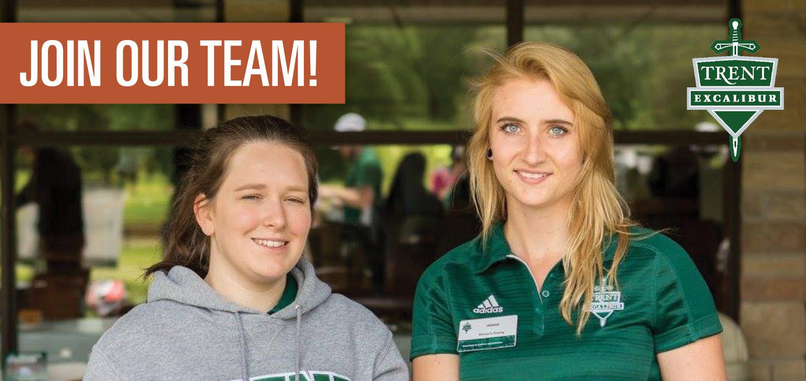 Two student staff members smile as they are working.